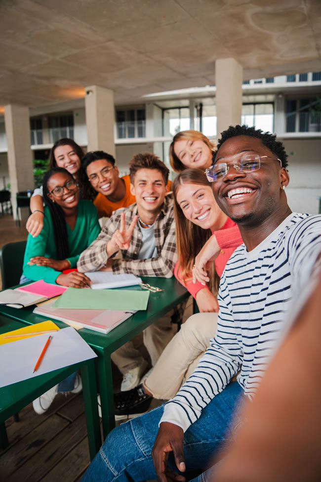 Happy college students taking a vertical selfie portrait together in library